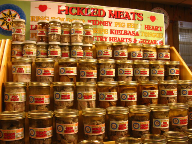 Jars of pickled meat on a display case.