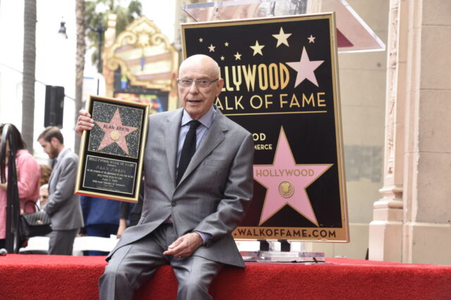 Alan Arkin holding up his Hollywood Walk of Fame star