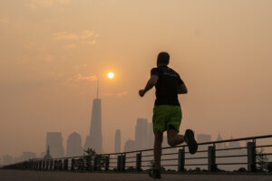 a man jogs through the Liberty State Park, while the smoke from Canada wildfires covers the Manhattan borough