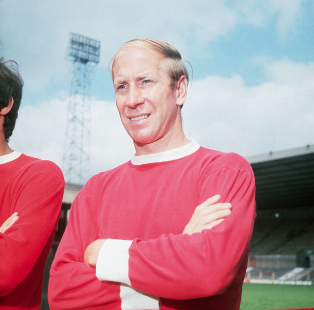 Bobby Charlton standing on the soccer pitch with another Manchester United player