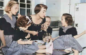 Joan Crawford standing with her four children in a kitchen.
