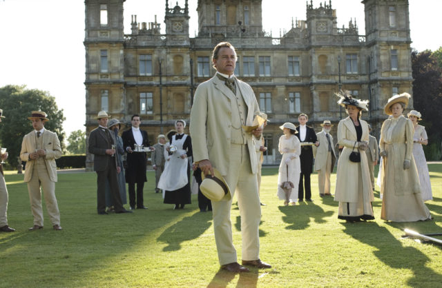 A still from Downton Abbey shows people gathered outside the estate