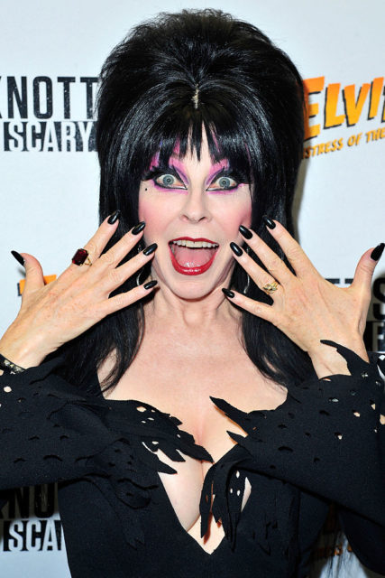 Elvira holding her hands up in surprise