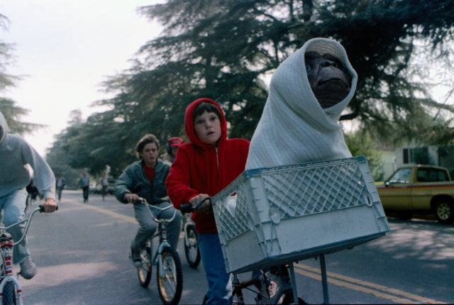 E.T. wrapped in a blanket riding in Elliott's bike basket.