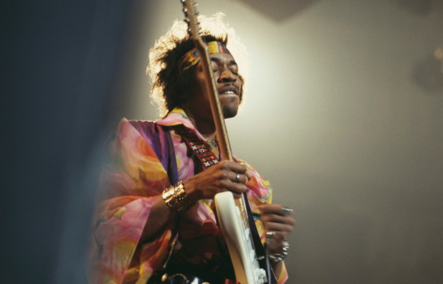 Jimi Hendrix plays guitar at a concert