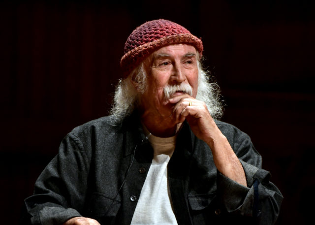 Headshot of David Crosby wearing a hat and looking to the side.