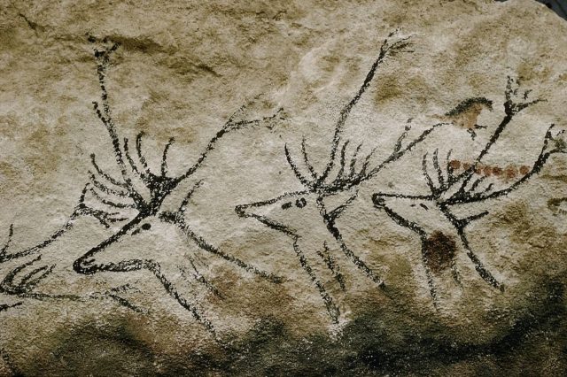 Rock painting of three stag like animals on a rock.