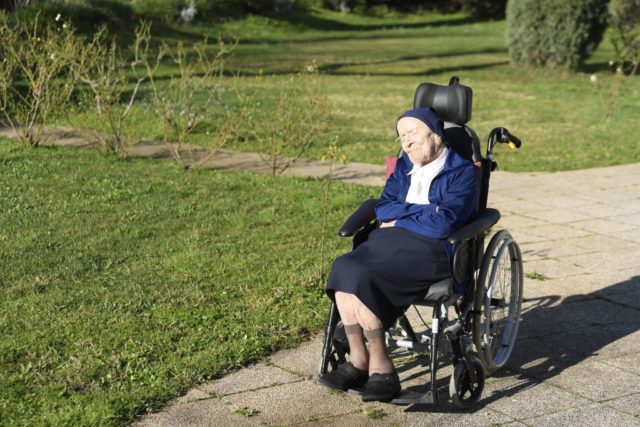 Lucile Randon in a wheelchair sitting in the sun outside.