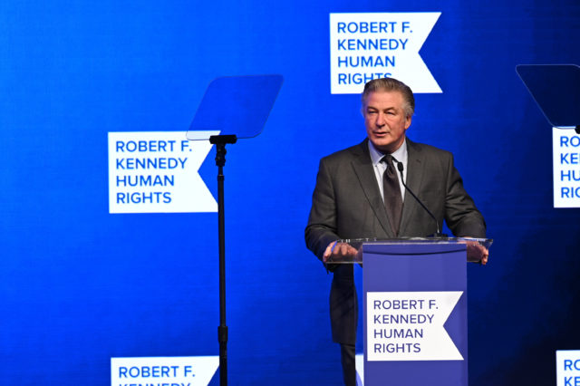 Alec Baldwin speaking at a podium 