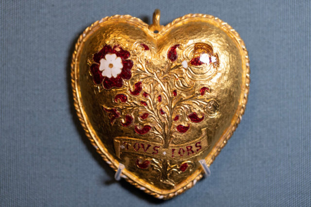 Gold heart shaped pendant with red stones in the shape of flowers and a tree.