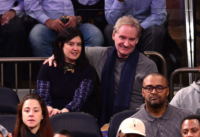 Kevin Kline sits with his arm around Phoebe Cates at a sports game.