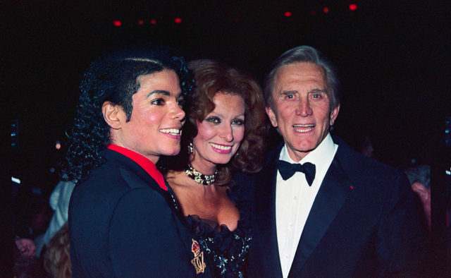 Michael Jackson, Sophia Loren, and Kirk Douglas in formal dress smile for a photograph together.