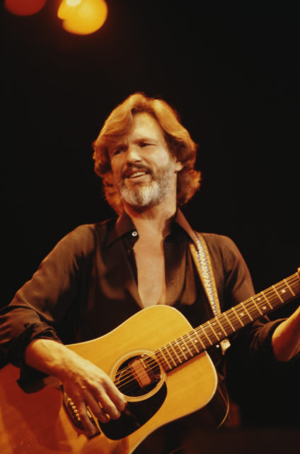 Kris Kristofferson playing the guitar on stage