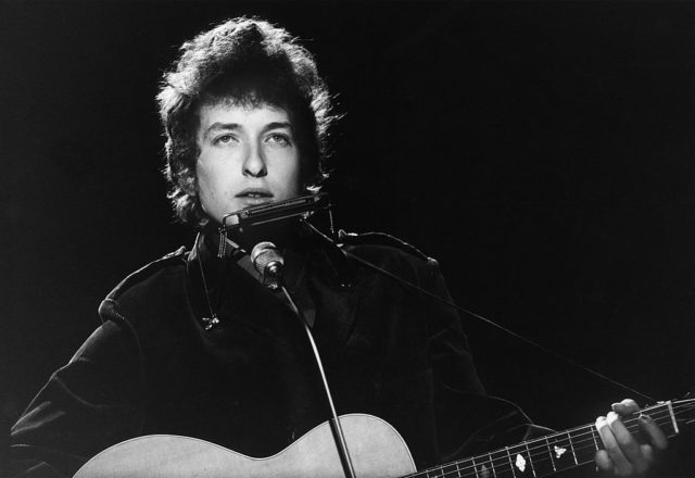 Bob Dylan plays guitar and harmonica during a performance