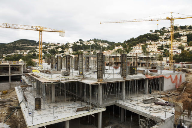 A construction site in progress with two cranes in the background.