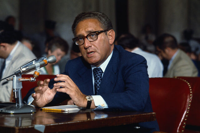 Henry Kissinger speaking at a microphone in the US Senate