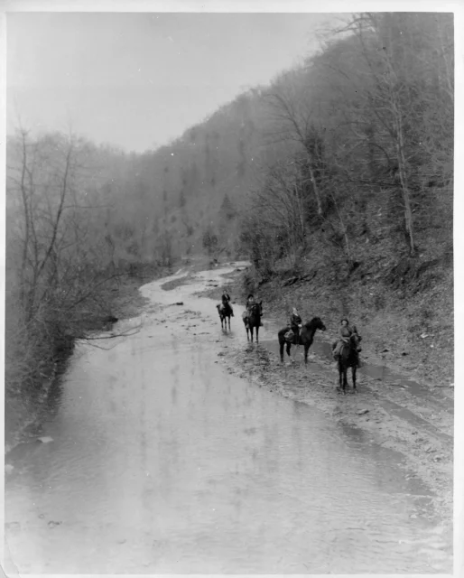 A group of women riding horses trudging through a river.