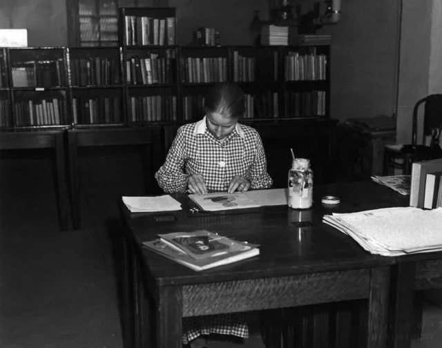 A woman working at a table in a library.