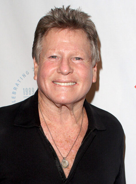 Ryan O'Neal standing on a red carpet