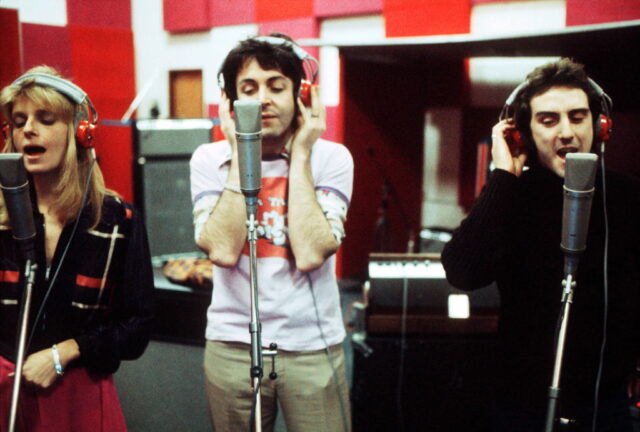 Linda McCartney, Paul McCartney and Denny Laine singing into microphones