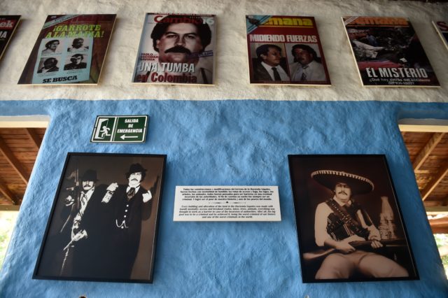 Different magazine covers and posters on a wall showing Pablo Escobar.