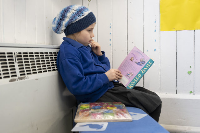 The side view of a child reading a Roald Dahl book