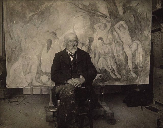 Photograph of Cezanne in his studio in front of a painting. 