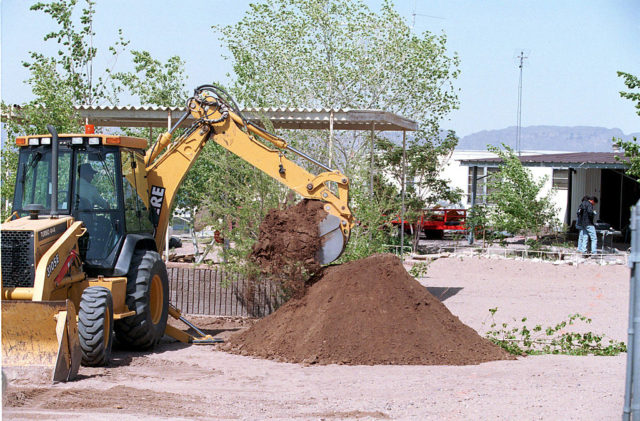 Excavator digging up the ground in front of David Parker Ray's trailer. 