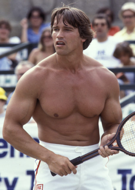 Shirtless Arnold Schwarzenegger holding a tennis racket.