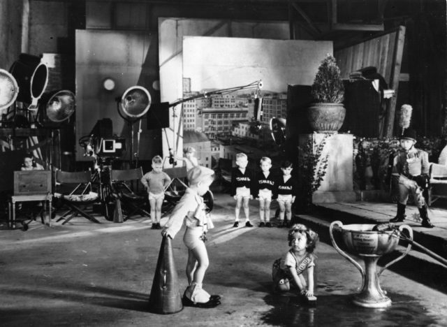 On the set of one of the baby burlesks, Shirley Temple is scene scrubbing the ground.