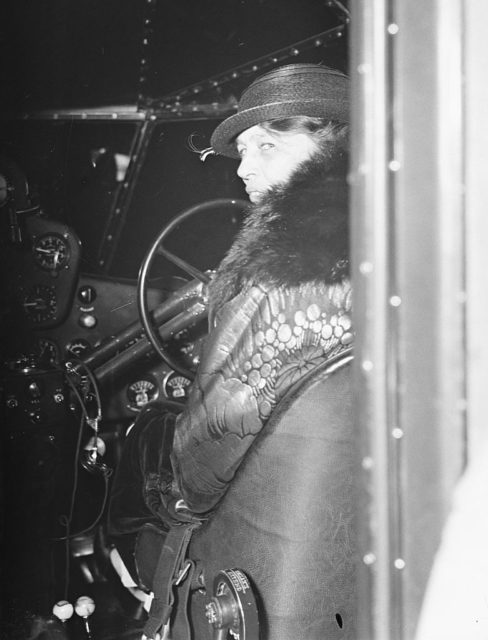 First Lady Eleanor Roosevelt sitting behind the wheel of a plane in flight.