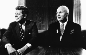 John F. Kennedy and Nikita Krushchev sitting beside each other on a couch.
