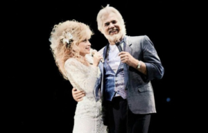 Dolly Parton in the arms of Kenny Rogers while the pair perform on stage.