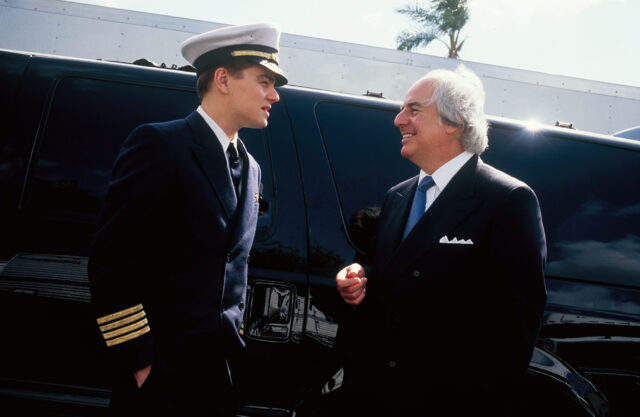 Leonardo DiCaprio in a pilot's uniform talking to Frank Abagnale Jr. in a black suit.