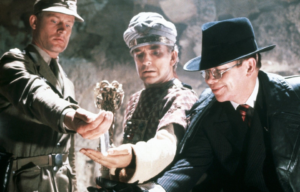 Wolf Kahler in German uniform, Ronald Lacey in all black with a black fedora, and Paul Freeman in robes and a turban.