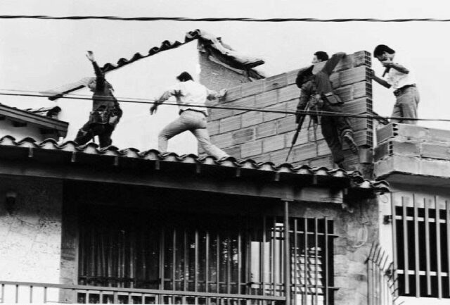 Men on a rooftop where Pablo Escobar was shot dead.