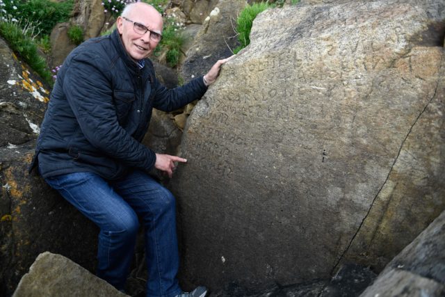 Michel Paugam points to a boulder that has an inscription dating back 230 years.