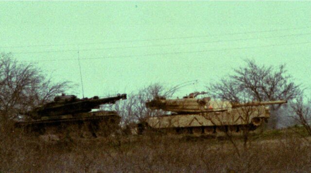 Two M1 Abrams tanks in the middle of shrubbery. 