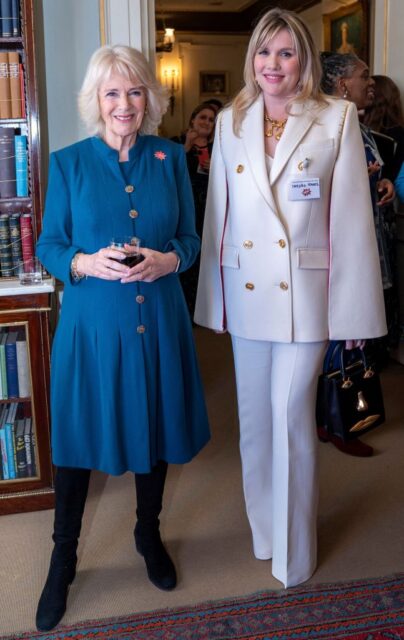 Emerald Fennell in a white pant suit, and Camilla, Queen Consort in a blue dress.
