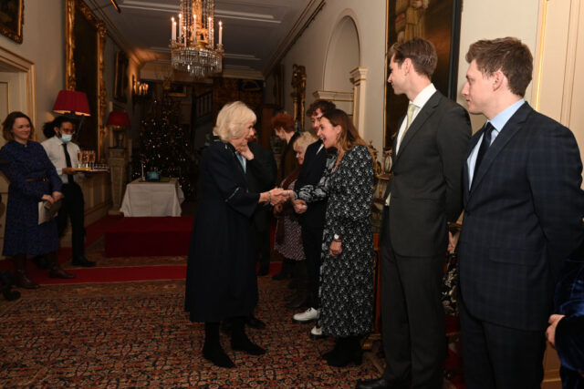 Camilla shakes hands with a lineup of people all in formal wear.