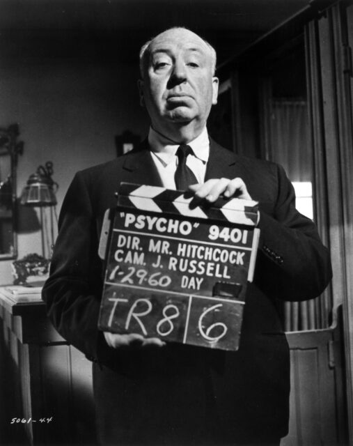 Alfred Hitchcock holding a clapperboard.