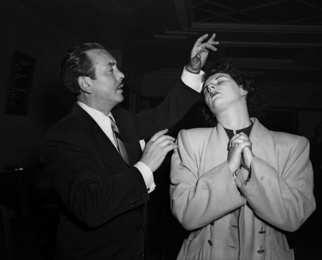 a man pretends to hynotize a woman during a stage act