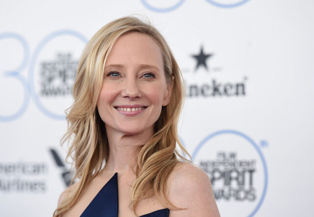 Anne Heche smiling while wearing a strapless blue dress.