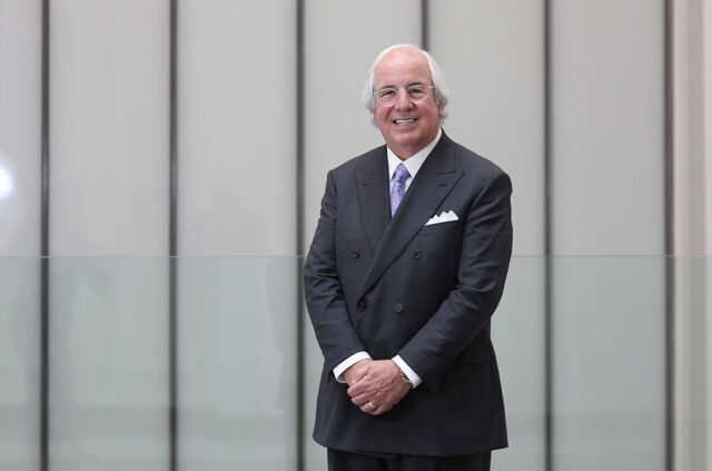 Frank Abagnale Jr. posing with his arms in front of him wearing a black suit.