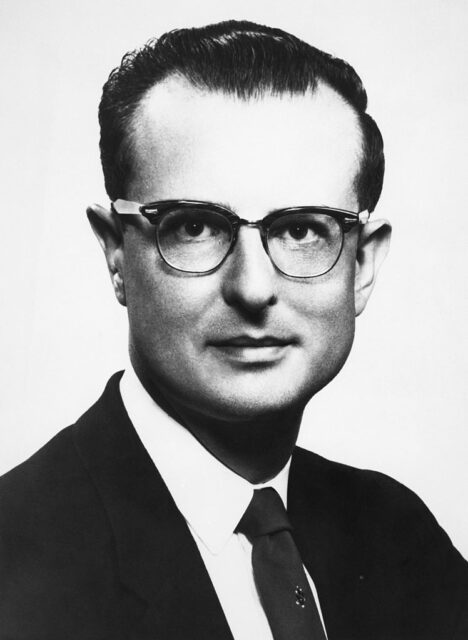 Headshot of John List in a black suit and glasses.