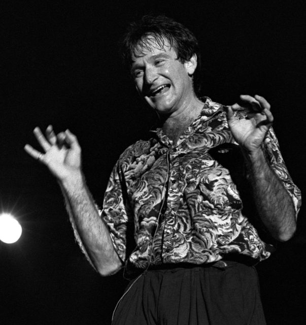 Comedian Robin Williams performs on stage in a black and white photo