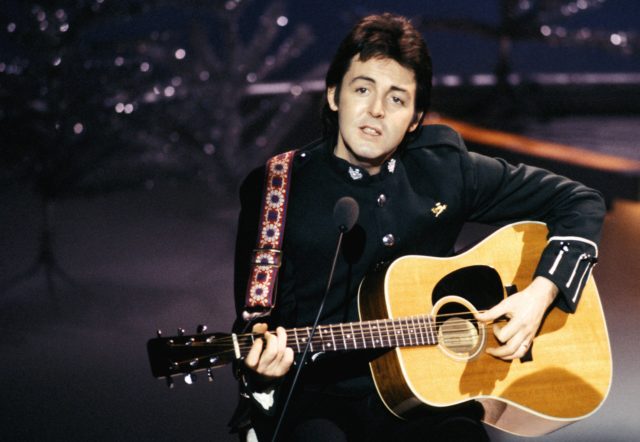 Paul McCartney, with Wings, performing on TV show, playing acoustic guitar