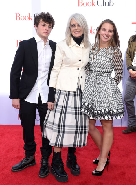 Diane Keaton standing on a red carpet with her two adopted children, Dexter and Duke.