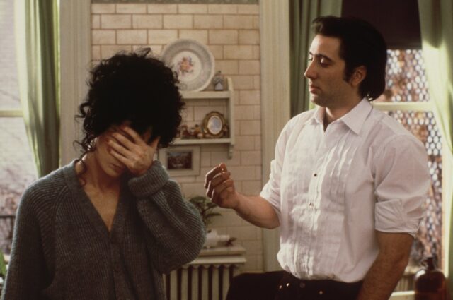 Cher holding her face in her hand while standing beside Nicolas Cage in a scene from "Moonstruck"