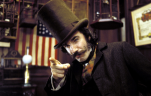 Daniel Day-Lewis as Bill the Butcher in a top hat and coat pointing at the viewer.